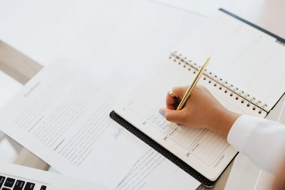 Agenda annoté à côté d’un contrat posé sur un bureau